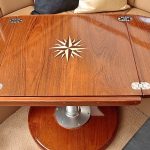 Teak boat table with inlaid design and leaves unfolded